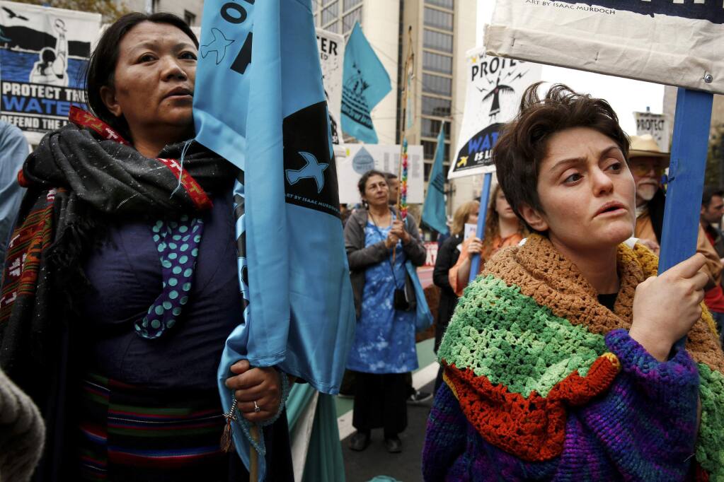 Tsering Yangkey, left, of Tibet, and Tanya Fromberg, of London, protest the Dakota Access oil pipeline along Market Street Tuesday, Nov. 15, 2016, in San Francisco, Calif. The protest brought thousands of demonstrators to the streets of San Francisco on Tuesday. Before sunrise, protesters formed a circle in a downtown plaza and burned sage before walking down Market Street. (Santiago Mejia/San Francisco Chronicle via AP)