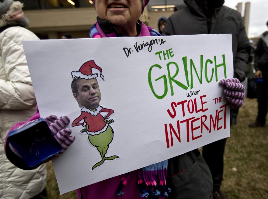 Diane Tepfer holds a sign with an image of Federal Communications Commission (FCC) Chairman Ajit Pai as the 'Grinch who Stole the Internet' as she protests near the FCC, in Washington, Thursday, Dec. 14, 2017, where the FCC is scheduled to meet and vote on net neutrality. The vote scheduled today at the FCC, could usher in big changes in how Americans use the internet, a radical departure from more than a decade of federal oversight. (AP Photo/Carolyn Kaster)