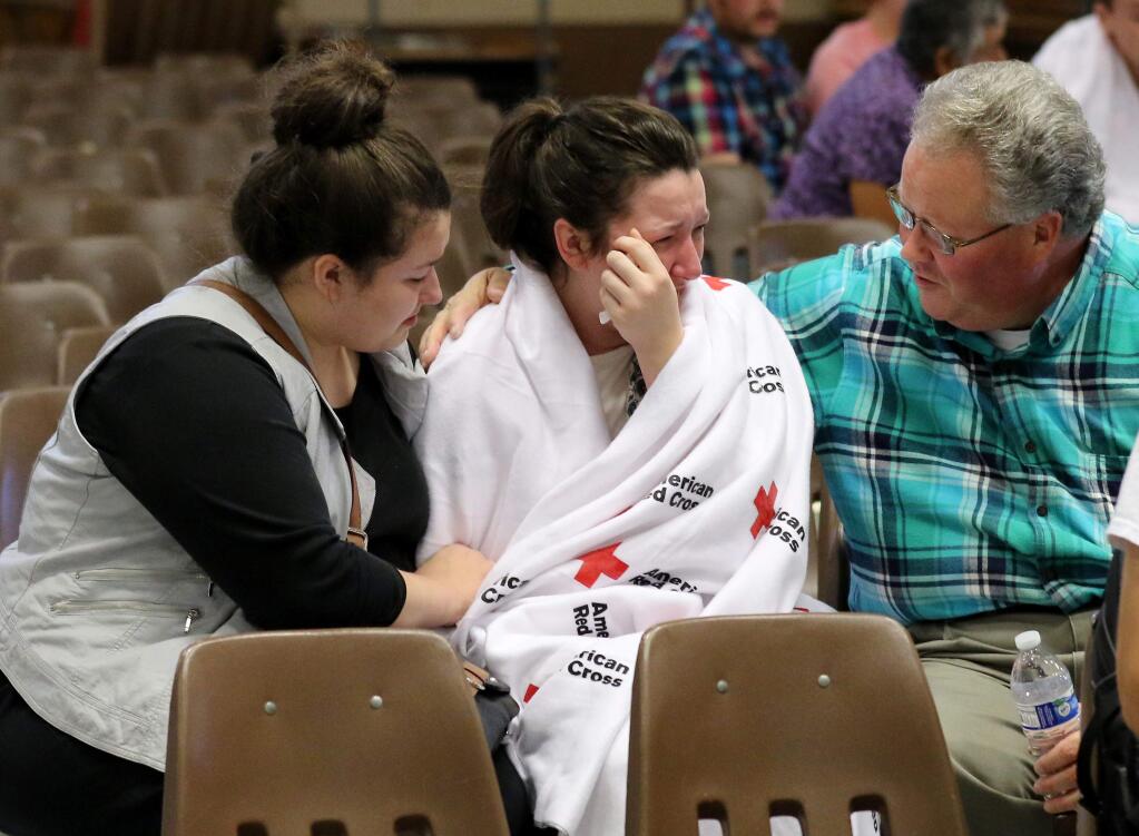 Hannah Miles, center, is reunited with her sister Hailey Miles, left, and father Gary Miles, right, after a shooting at Umpqua Community College in Roseburg, Ore., on Thursday, Oct. 1, 2015. (AP Photo/Ryan Kang)