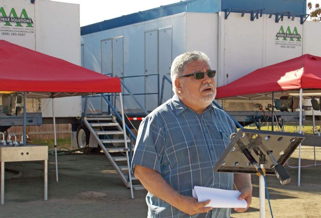 In this photo taken Monday, Nov. 17, 2014, the Rev. Ramon Hernandez of Iglesia Emmanuel church speaks during the opening of portable showers being made available to residents whose wells have gone dry. Hundreds of people living in the drought-stricken California farm town could soon be taking their first hot shower in months after county officials set up the portable facilities in the church parking lot. Until now, many have been forced to bathe from buckets and drink bottled water. (AP Photo/The Porterville Recorder, Rick Elkins)