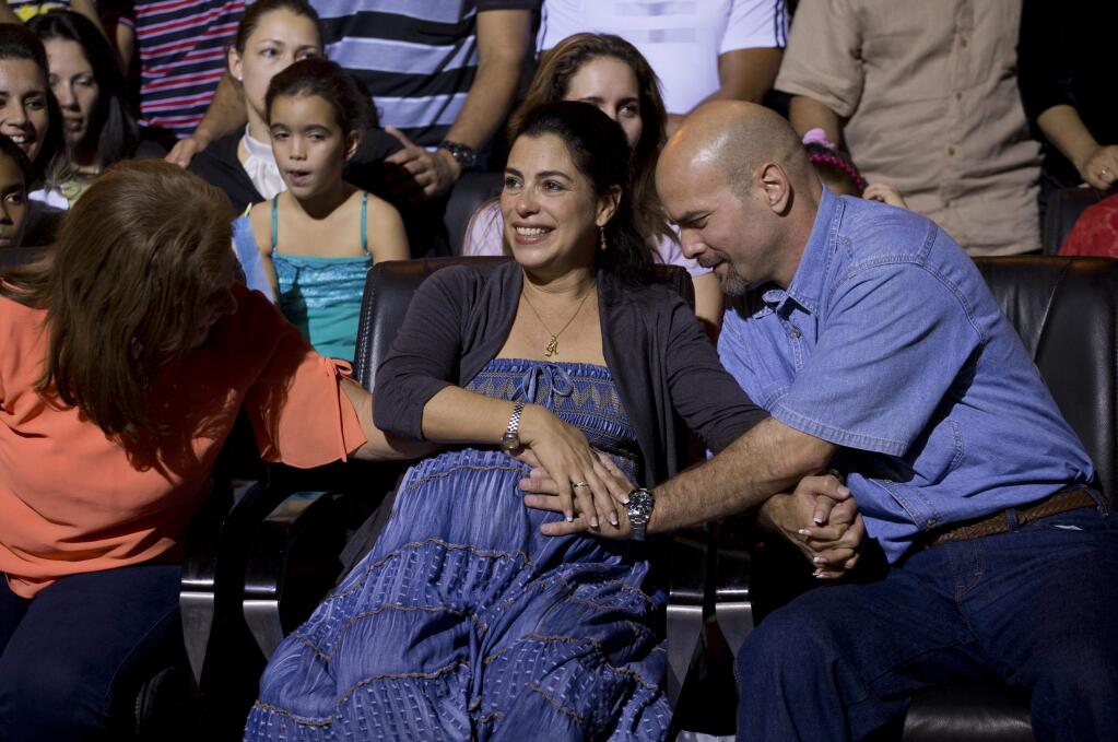 Gerardo Hernandez, right, member of 'The Cuban Five,' touches the belly of his pregnant wife Adriana Perez, during a concert of singer Silvio Rodriguez in Havana, Cuba, Saturday, Dec. 20, 2014. Hernandez flew back to their homeland on Wednesday in a quiet exchange of imprisoned spies, part of a historic agreement to restore relations between the two long-hostile countries. (AP Photo/Ramon Espinosa)