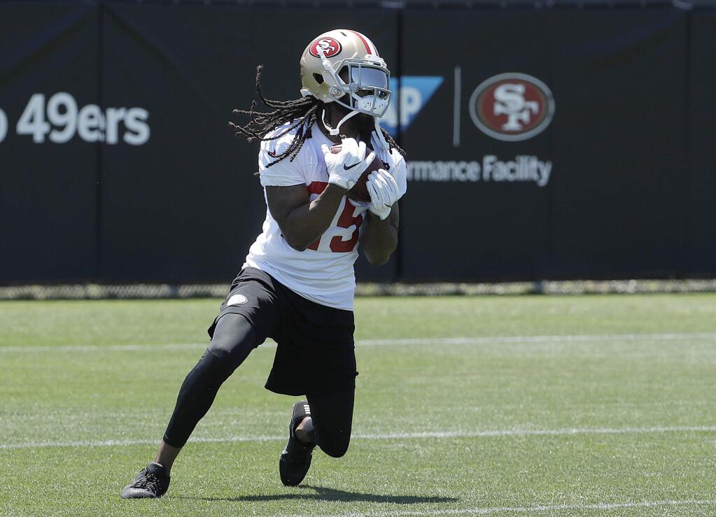 FILE - In this June 13, 2018, file photo, San Francisco 49ers cornerback Richard Sherman catches a ball during NFL football practice at the team's headquarters in Santa Clara, Calif. Sherman has been cleared to practice for the 49ers at the start of training camp. Sherman joined San Francisco after getting released by rival Seattle following season-ending surgery to repair a ruptured Achilles tendon. Sherman pronounced himself 100 percent when he reported to camp Wednesday, July 25, and will take part in the team's first practice Thursday. Sherman earned a $2 million bonus for passing his physical. (AP Photo/Jeff Chiu, File)