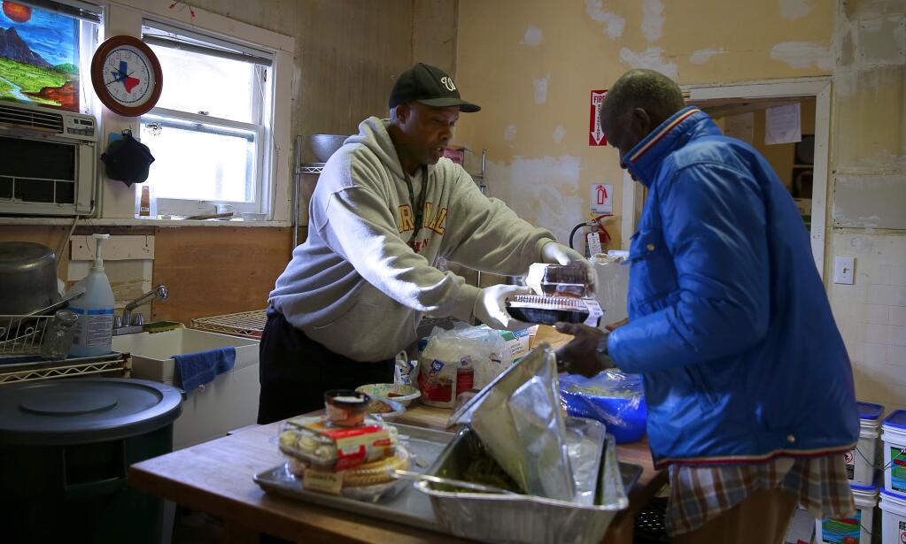 Rodney Hill, left, hands out some food to Mark Morton at the Catholic Charities Homeless Services Center, in Santa Rosa, on Friday, January 15, 2016. Hill has been selected as the first resident for permanent housing at the newly converted Palms Inn.(Christopher Chung/ The Press Democrat)