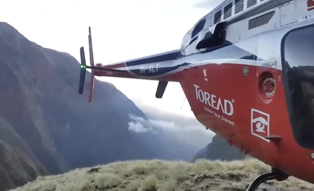 In this grab taken from video provided by SIMRIK AIR, a helicopter lands close to a storm site after searching for missing mountaineers on the Gurja Himal mountain, in Nepal, Saturday, Oct. 13, 2018. Seven people, including South Korean climbers, were killed and two more are missing on Gurja Himal mountain after a strong storm swept through their base camp, Nepalese police said Saturday. (SIMRIK AIR via AP)