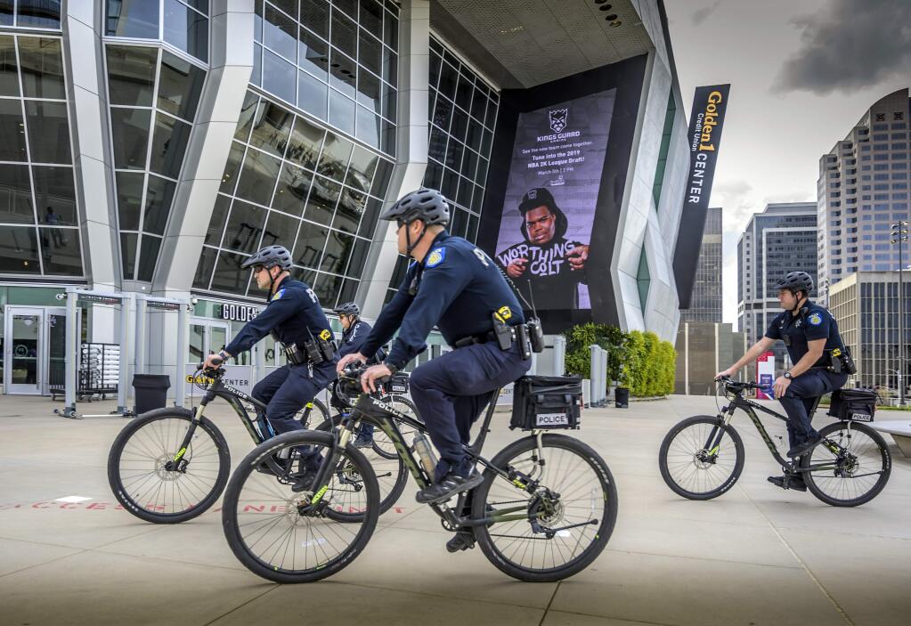 File - In this March 4, 2019, file photo, Sacramento, Calif., police officers ride bicycles near the Golden 1 Center. Organizers of a pride parade in California reversed course and said uniformed police officers will be welcome at the festivities. The announcement came Thursday, June 6, 2019, after the Sacramento LGBT Community Center and Sacramento Police Department created a partnership that will include a police liaison and training for new officers with discussions about bias. (Hector Amezcua/Sacramento Bee via AP, File)