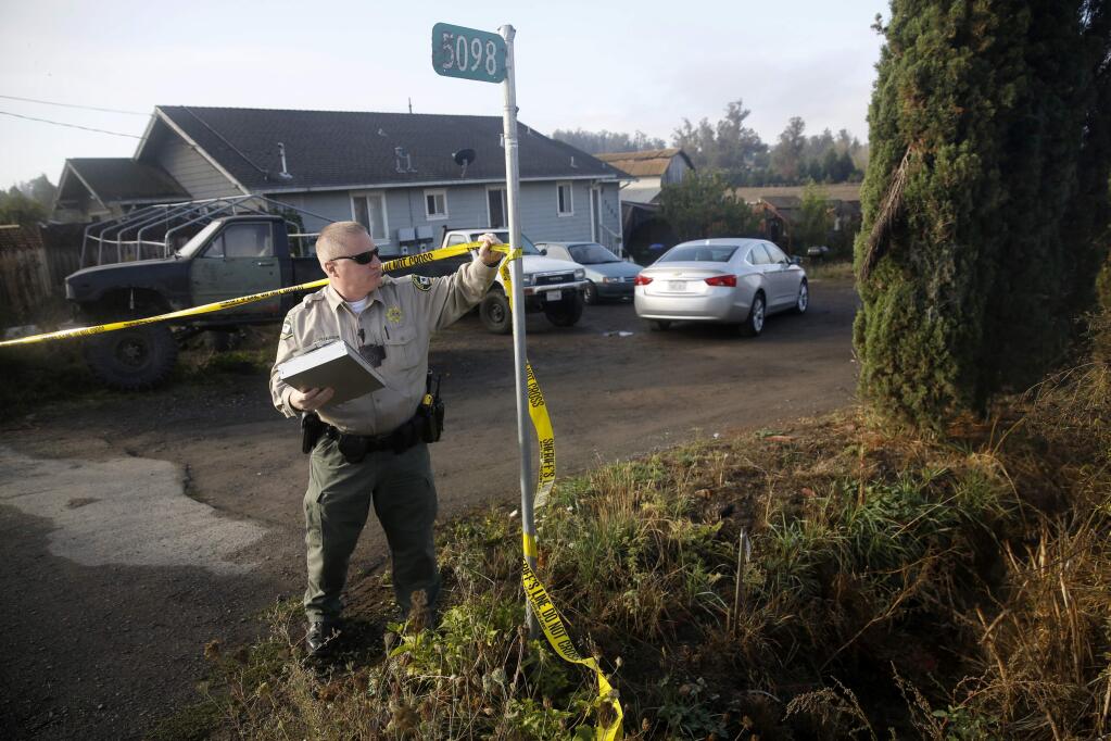 Sonoma County sheriff's deputy Joel Pedersen adjusts the crime scene tape at a triple shooting on the 5000 block of Highway 116 South on Sunday, October 16, 2016 near Sebastopol, California . (BETH SCHLANKER/ The Press Democrat)