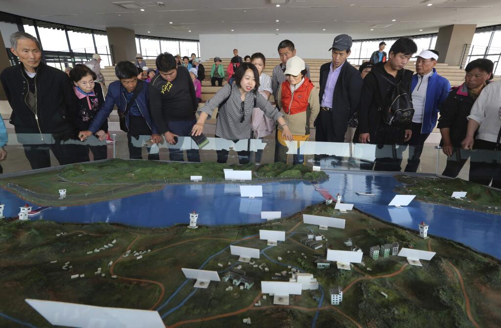 Visitors look at a diorama of the two Koreas borderland at the unification observatory in Paju, near the border with North Korea, South Korea, Thursday, April 26, 2018. North Korean leader Kim Jong Un and South Korean President Moon Jae-in will plant a commemorative tree and inspect an honor guard together after Kim walks across the border Friday for their historic summit, Seoul officials said Thursday. (AP Photo/Ahn Young-joon)