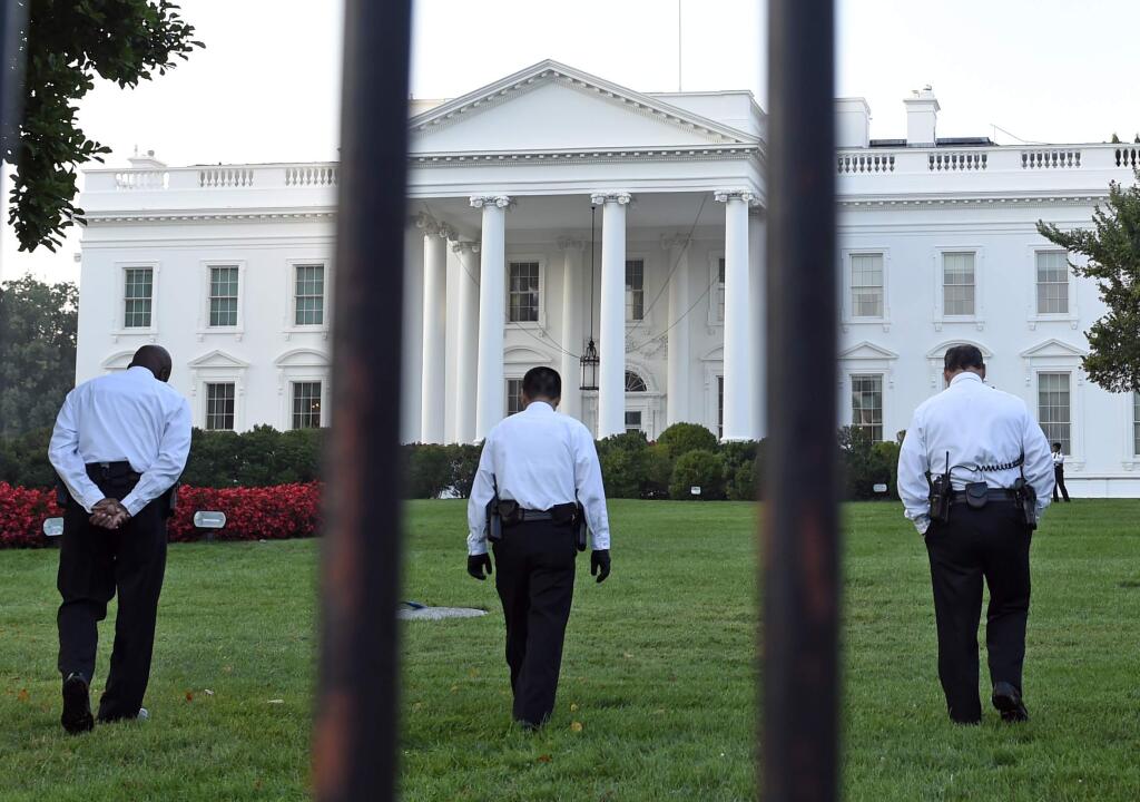 Uniformed Secret Service officers walk along the lawn at the White House in Washington, Saturday, Sept. 20, 2014. (AP Photo/Susan Walsh)