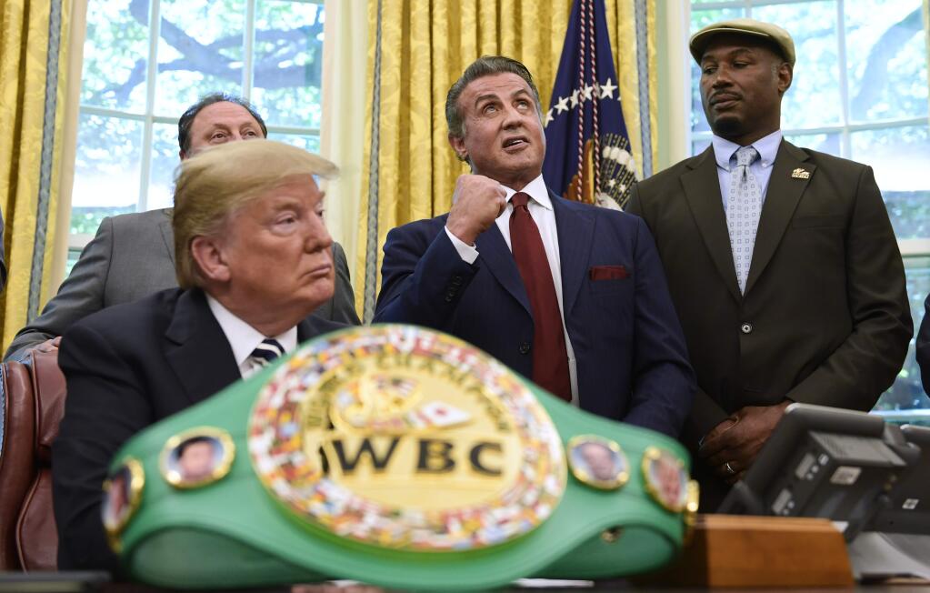 President Donald Trump, left, and heavyweight champion boxer, Lennox Lewis, right, watch as Sylvester Stallone gestures in the Oval Office of the White House in Washington, Thursday, May 24, 2018, where Trump granted a posthumous pardon to Jack Johnson, boxing's first black heavyweight champion. (AP Photo/Susan Walsh)
