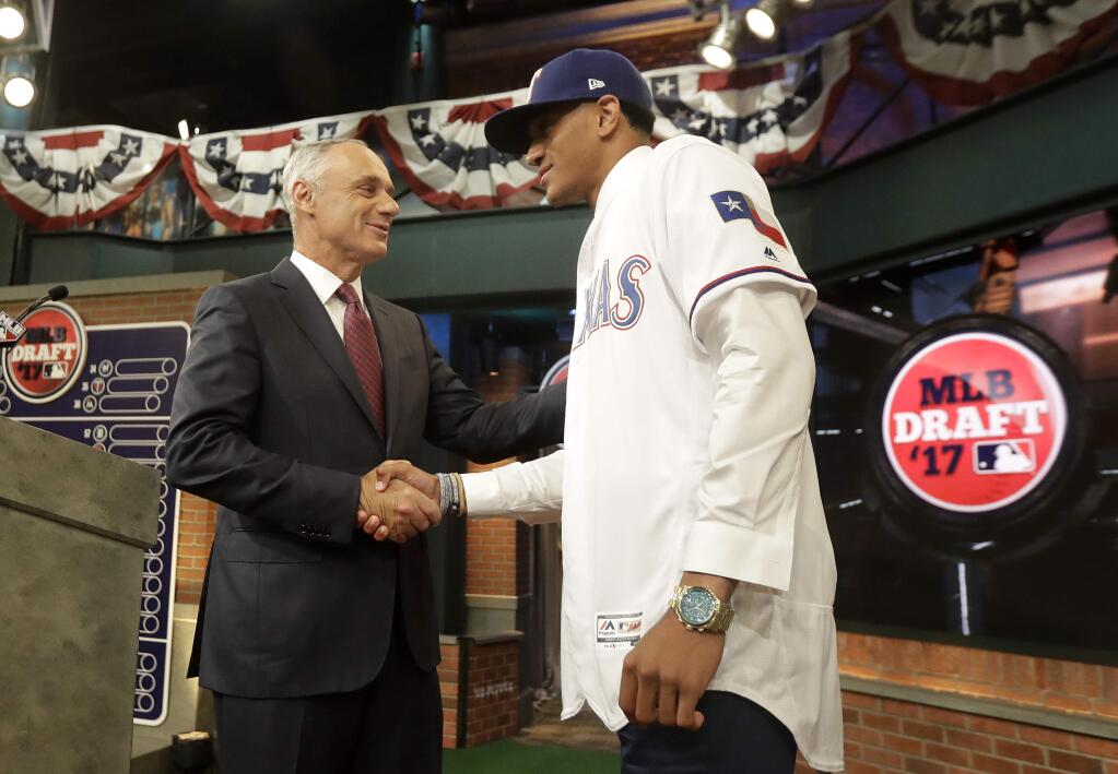 Baseball commissioner Rob Manfred, left, shakes hands with Bubba Thompson, an outfielder from McGill-Toolen Catholic High School in Mobile, Ala., after being selected No. 26 by the Texas Rangers in the first round of the Major League Baseball draft, Monday, June 12, 2017, in Secaucus, N.J. (AP Photo/Julio Cortez)