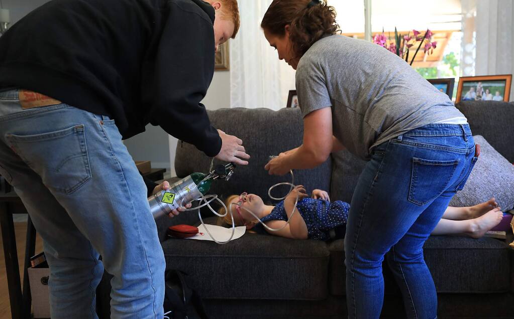 As Brooke Adams, 5, seizes, her brother Luke, 17, helps his mother Jana calmly give oxygen after the five-year-old was treated with cannabis-based medication (CBD), Monday, July 23, 2018 at their home in Santa Rosa. Brooke has Dravet syndrome, a rare genetic dysfunction of the brain. The CBD cuts the seizing to just minutes. (KENT PORTER/ PD)