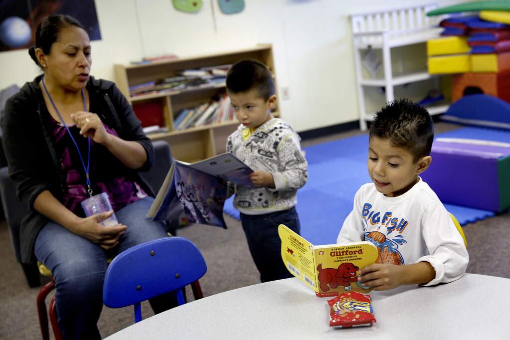 Andy Ezparza, 4, right, and Jonny Guzman, 3, read with staff member Maria Guido during a day care session with the Via Esperanza program on the Cook Middle School in Santa Rosa, on Tuesday, May 12, 2015. (BETH SCHLANKER/ The Press Democrat)