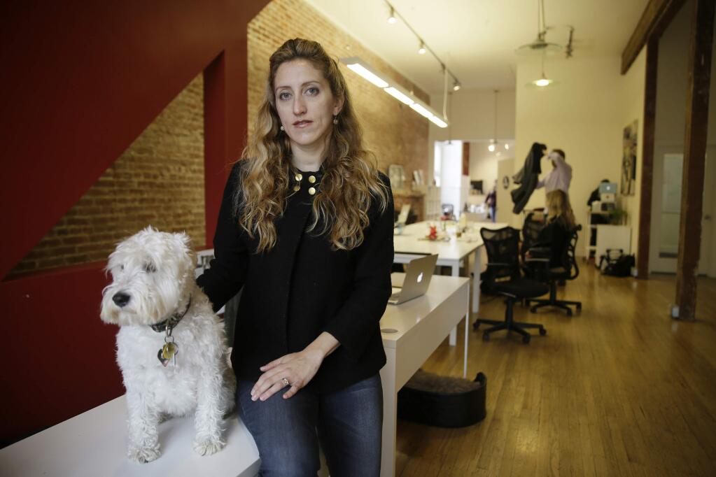 In this photo taken Tuesday, Feb. 21, 2017, Ashley Breinlinger, a senior vice president at BOCA Communications, poses with her dog Bella at her offices in San Francisco. Breinlinger describes this flu season as the ugliest she's seen in 10 years, in terms of how sick people are getting. (AP Photo/Eric Risberg)