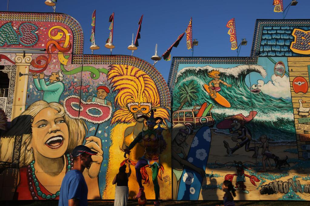 People walk past the Helm and Sons attractions at the Sonoma County Fair, Wednesday, July 30, 2014. (Crista Jeremiason / The Press Democrat)