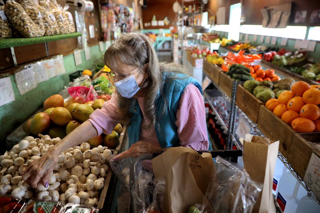 Janet Kelly, who is a diabetic with kidney and heart problems, wears a mask as she stocks up on produce at Palace of Fruit in Penngrove on Tuesday, March 17, 2020. (BETH SCHLANKER/ The Press Democrat)