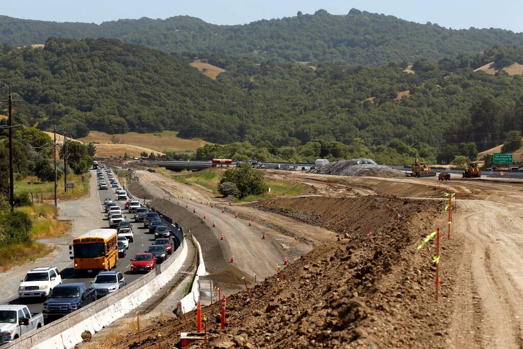 Motorists drive northbound in afternoon traffic on Highway 101, beside the road construction zone south of Petaluma, on Wednesday, May 30, 2018. The new bridge over San Antonio Creek is seen at center, in the background. (Alvin Jornada / The Press Democrat)