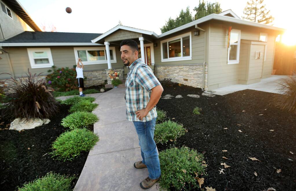 Jaime Licea replaced his aging water intensive lawn at his home in Healdsburg with drought tolerant plants, to set a good example, Friday, Nov. 7, 2014. In the background is his son, Jayson. (KENT PORTER/ PD)