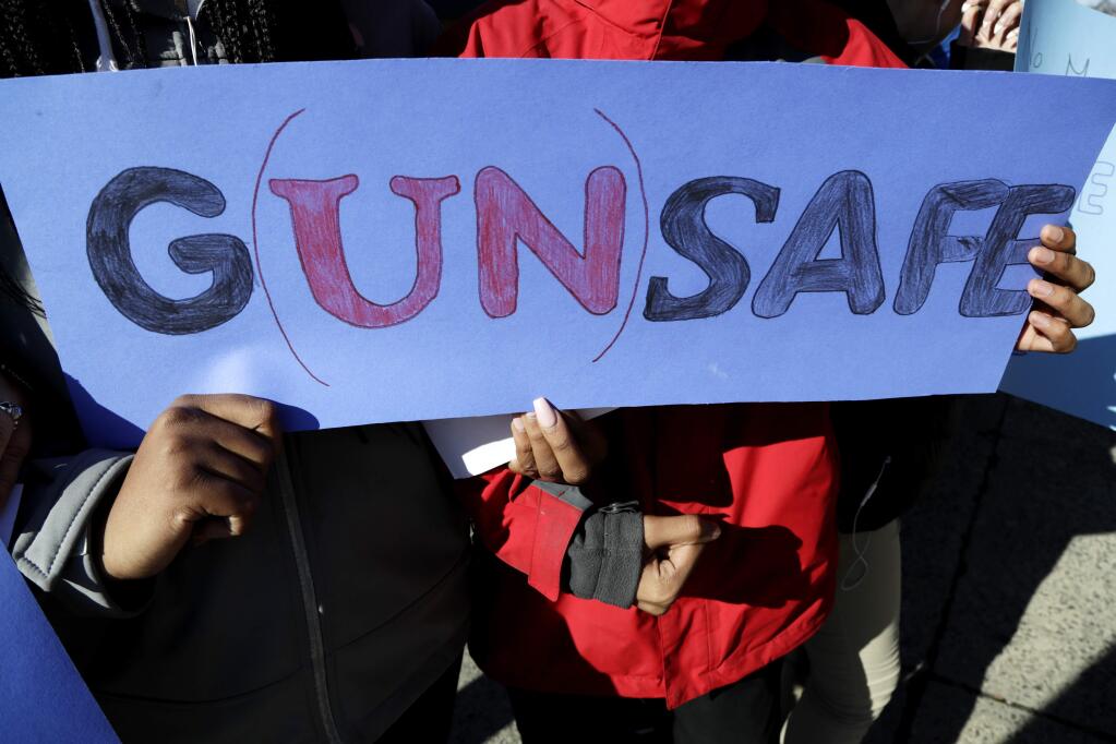 James Ferris High School freshmen Diamond Bryant, left, and James Williams interlock arms while holding a sign during a student walkout, Wednesday, March 14, 2018, in Jersey City, N.J. Students across the country participate in walkouts Wednesday to protest gun violence, one month after the deadly shooting inside a high school in Parkland, Fla. (AP Photo/Julio Cortez)