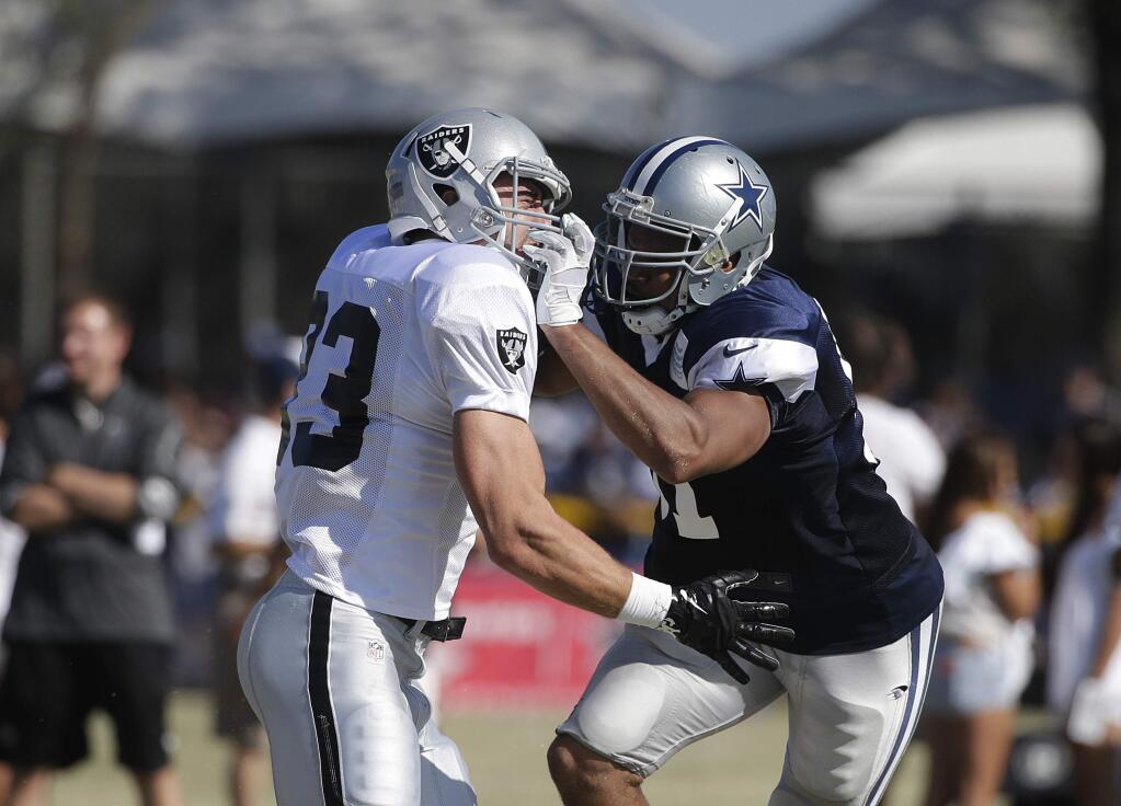Dallas Cowboys linebacker Kyle Wilber, right, grabs Oakland Raiders strong safety Tyvon Branch's helmet during a joint football practice on Tuesday, Aug. 12, 2014, in Oxnard, Calif. (AP Photo/Jae C. Hong)