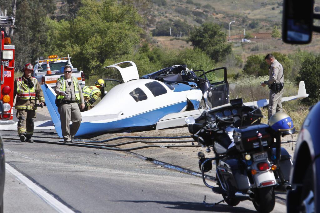 Emergency personnel investigate the scene of plane crash, Saturday, April 2, 2016 in Fallbrook, Calif. A small plane crashed on a Southern California freeway Saturday and struck a car, killing one person and injuring five others, authorities said. (Don Boomer/The San Diego Union-Tribune via AP) NO SALES; MANDATORY CREDIT