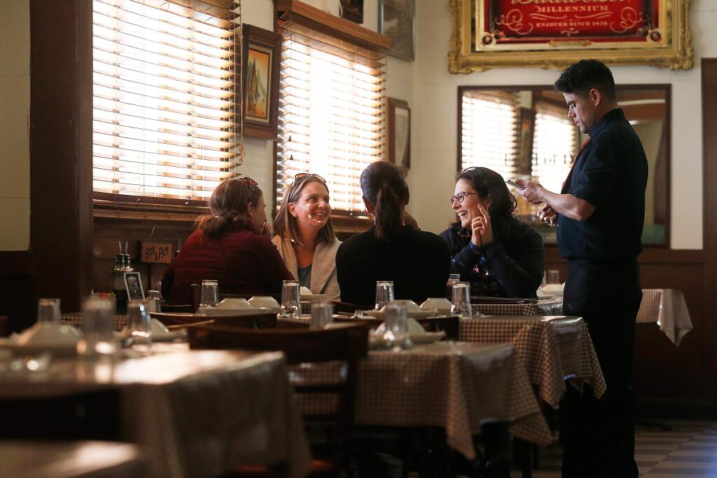 Dinucci's server Dustin Covington, right, takes the orders of college friends, from left, Rebecca Cruise, Stephanie Egbers-Meyers, Katie Jones, and Margaret Galileo who reunite to catch up and celebrate birthdays at Dinucci's Italian Dinners in Valley Ford, California, on Thursday, May 31, 2018. (Alvin Jornada / The Press Democrat)