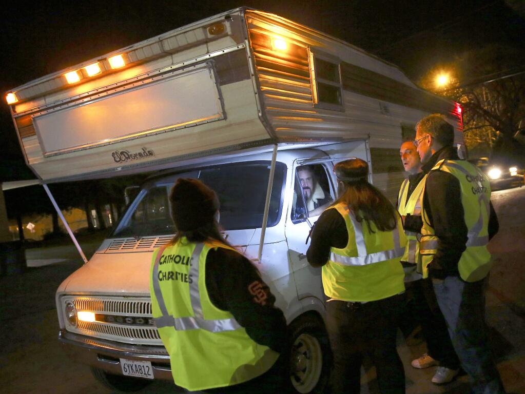 Volunteers with Catholic Charities welcome Frederick Helmke to the RV park by the Sonoma County Fairgrounds so that he can safely park his camper there for the night in Santa Rosa on Monday, Feb. 3, 2014. (Conner Jay/The Press Democrat)