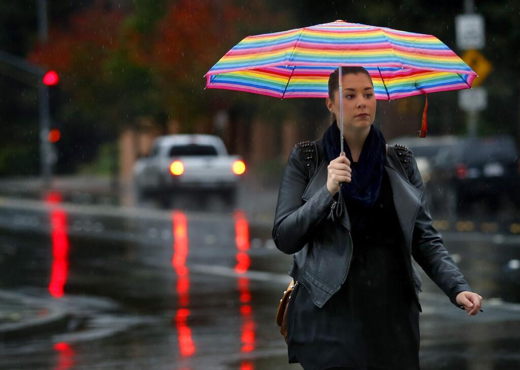 Windsor High School freshmen Jenna Strom, right, and Ashley Swanson make their way to school in the rain through the Windsor Town Green, on Wednesday morning, October 28, 2015. (Christopher Chung/ The Press Democrat)