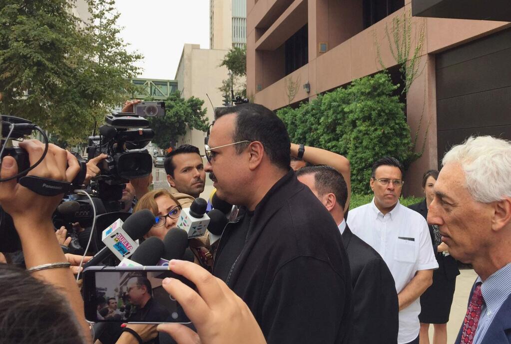 Mexican-American singer Pepe Aguilar, center, with attorney Jeremy Warren, right, speaks to reporters outside San Diego federal court, following the sentencing of the singer's son, Jose Emiliano Aguilar, in San Diego on Tuesday, Sept. 5, 2017. Jose Emiliano Aguilar was sentenced to time served Tuesday after being arrested at a U.S.-Mexico border crossing on allegations of attempting to smuggle four Chinese nationals into the United States. (Kristina Davis/The San Diego Union-Tribune via AP)