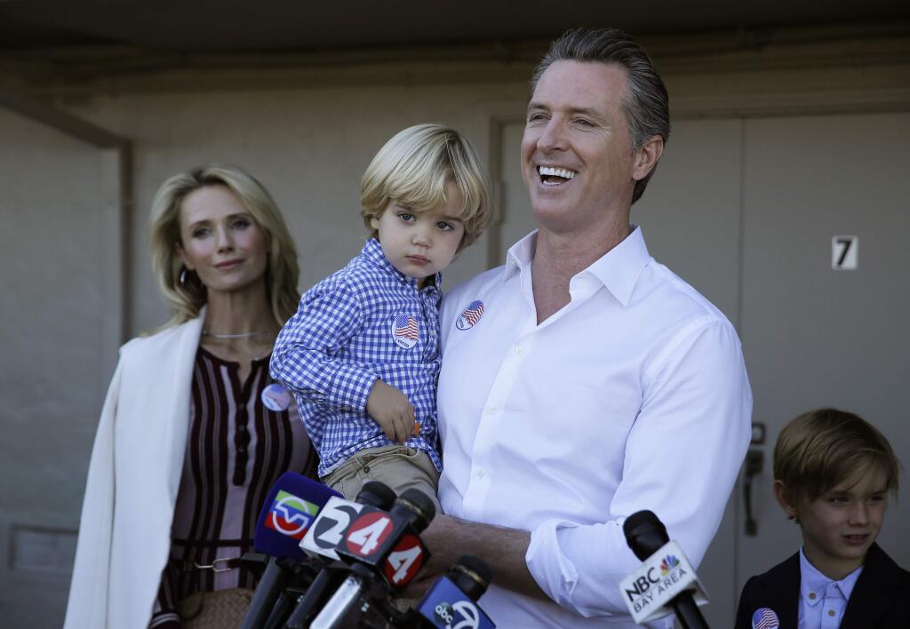 California gubernatorial Democratic candidate Gavin Newsom holds his son Dutch, 2, and talks with reporters after voting Tuesday, Nov. 6, 2018, in Larkspur, Calif. At left is his wife, Jennifer Siebel Newsom and at right his son Hunter, 7. (AP Photo/Eric Risberg)