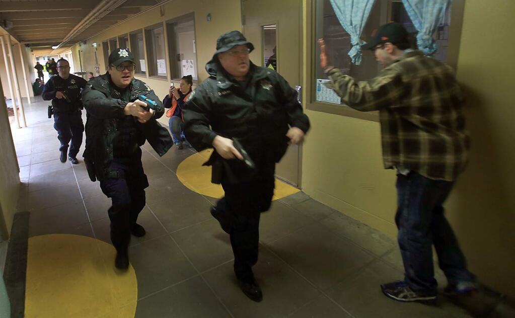 Cloverdale police officers Dave Haas, right, leads fellow officers Jim Stratton and Marcos Perez through an active shooter drill in the halls of Washington Elementary School in Cloverdale, Friday March 24, 2017. At right is faux victim Colin Wolford, a police cadet with the Santa Rosa Junior College training program. (Kent Porter / The Press Democrat) 2017