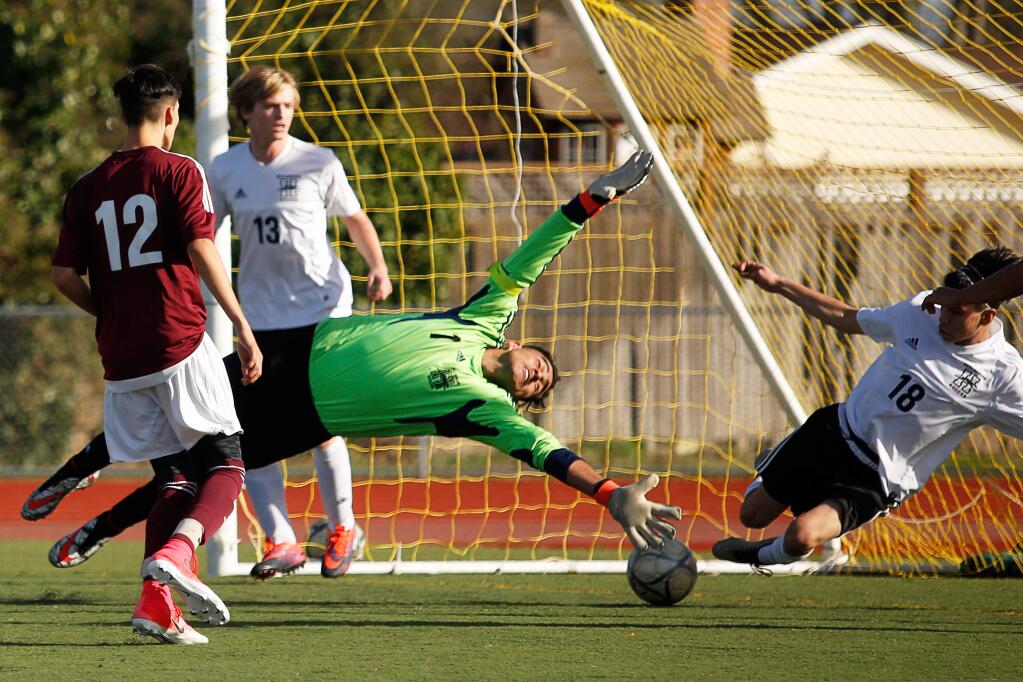 Healdsburg goalkeeper Javier Aguilar, center, and James Valencia, right, both dive to block a shot on goal by Piner's Adrian Gonzalez (15) during the first half of a boys varsity soccer match between Healdsburg and Piner high schools on Saturday, Jan. 27, 2018. Piner won 1-0, avenging an earlier loss to Healdsburg and improving to 7-1 in Sonoma County League play. (Alvin Jornada / The Press Democrat)