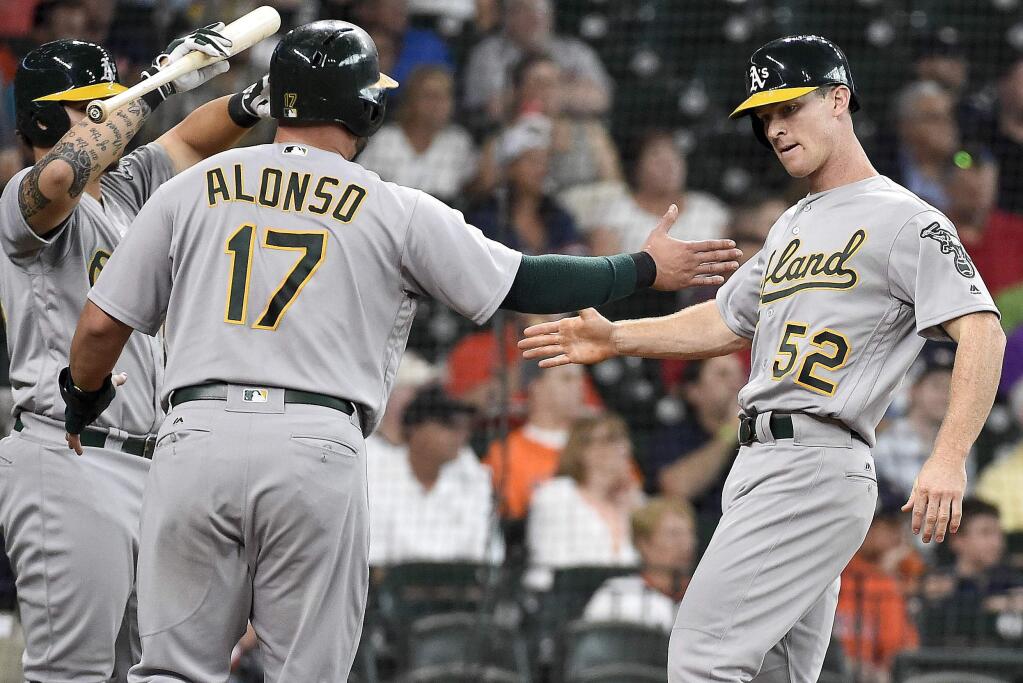 Oakland Athletics' Joey Wendle (52) slpas hands with Yonder Alonso (17) after scoring a run on Jake Smolinski's two-run triple in the second inning of a baseball game against the Houston Astros, Wednesday, Aug. 31, 2016, in Houston. (AP Photo/Eric Christian Smith)