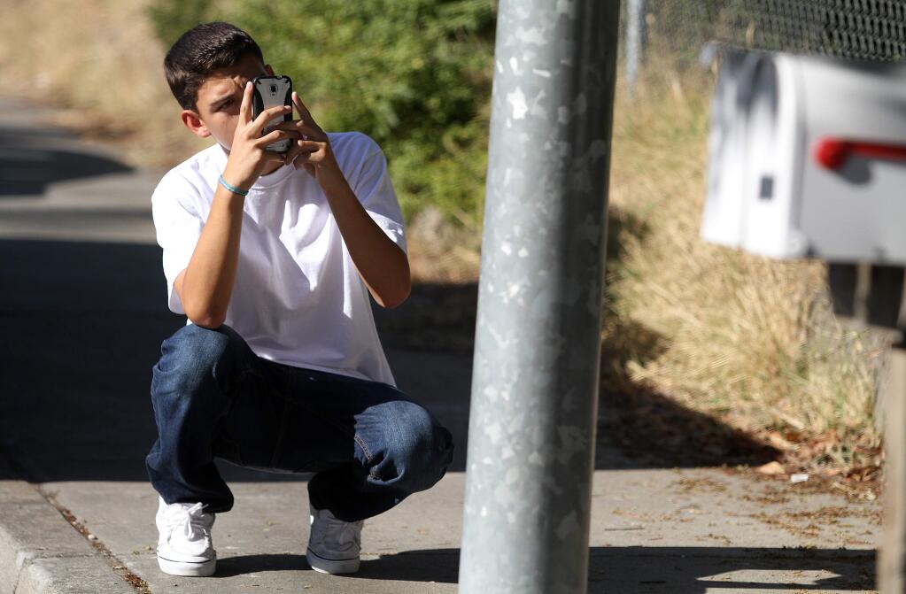 Erick Tinajero takes a photo of graffiti on a poll on Moorland Ave., Tuesday, August 26, 2014. Tinajero, a junior at Elsie Allen High School, is participating in the Community Action Partnership of Sonoma County program where students go out with their smartphones to take photos of things they like and dislike in their community. (Crista Jeremiason / The Press Democrat)