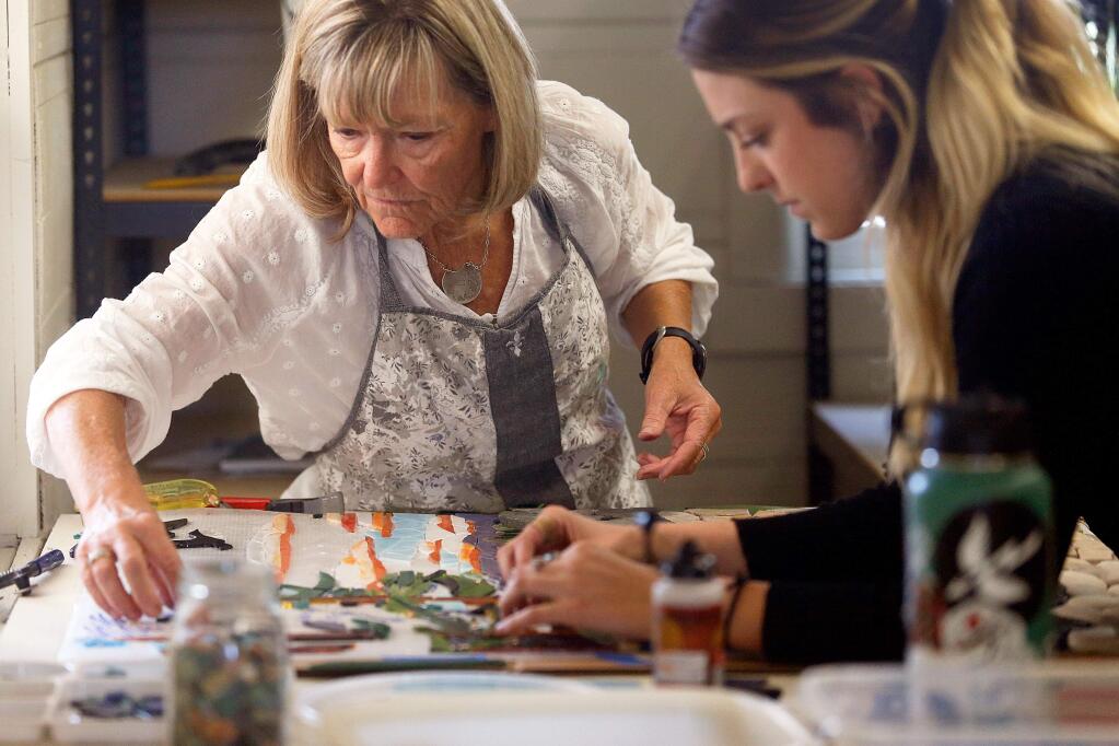 Barbara Ihde, left, and lead artist Angelina Duckett place glass pieces on a memorial mosaic for Ihde's late husband, former Sonoma County Sheriff and Goodwill CEO Mark Ihde, at Artstart in Santa Rosa, California, on Thursday, August 30, 2018. (Alvin Jornada / The Press Democrat)