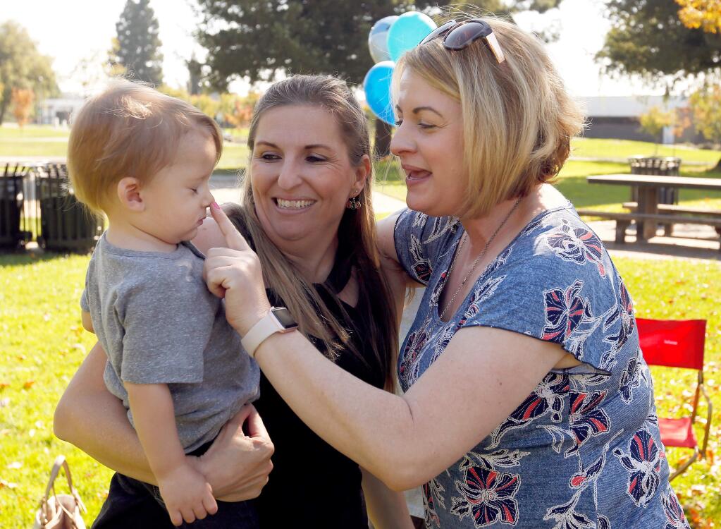Former Hilton Sonoma Wine Country human resources director Lenora Olson, right, greets former banquet server Karen Hoj and her son Carson during a reunion of employees of the hotel which burned down during the Tubbs Fire, at Finley Park in Santa Rosa, California, on Saturday, October 20, 2018. (Alvin Jornada / The Press Democrat)