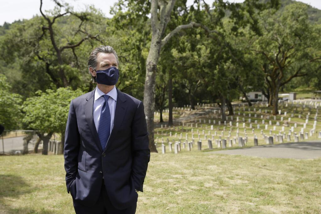 California Gov. Gavin Newsom looks out at rows of graves before a wreath laying ceremony in the cemetery at the Veterans Home of California Friday, May 22, 2020, in Yountville, Calif. (AP Photo/Eric Risberg, Pool)