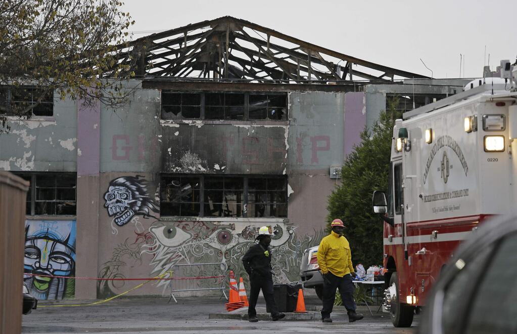 A pair of Oakland fire officials walk past the remains of the Ghost Ship warehouse fire Wednesday, Dec. 7, 2016, in Oakland, Calif. The fire that killed 36 people during a party at an Oakland warehouse started on the ground floor and quickly raged, with smoke billowing into the second level and trapping victims whose only escape route was through the flames, federal investigators said Wednesday. (AP Photo/Eric Risberg)