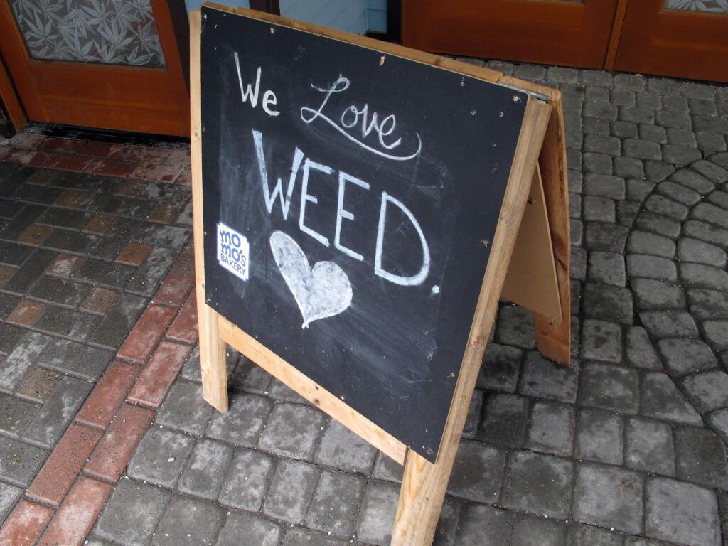 In this Feb. 27, 2018, photo, a sign reading, 'We Love Weed' stands outside a state-licensed marijuana shop in downtown Juneau, Alaska. Taking a cue from the fight over immigration, some states that have legalized marijuana are considering providing so-called sanctuary status for licensed pot businesses, hoping to protect the young industry from a shift in federal enforcement policy. (AP Photo/Becky Bohrer)