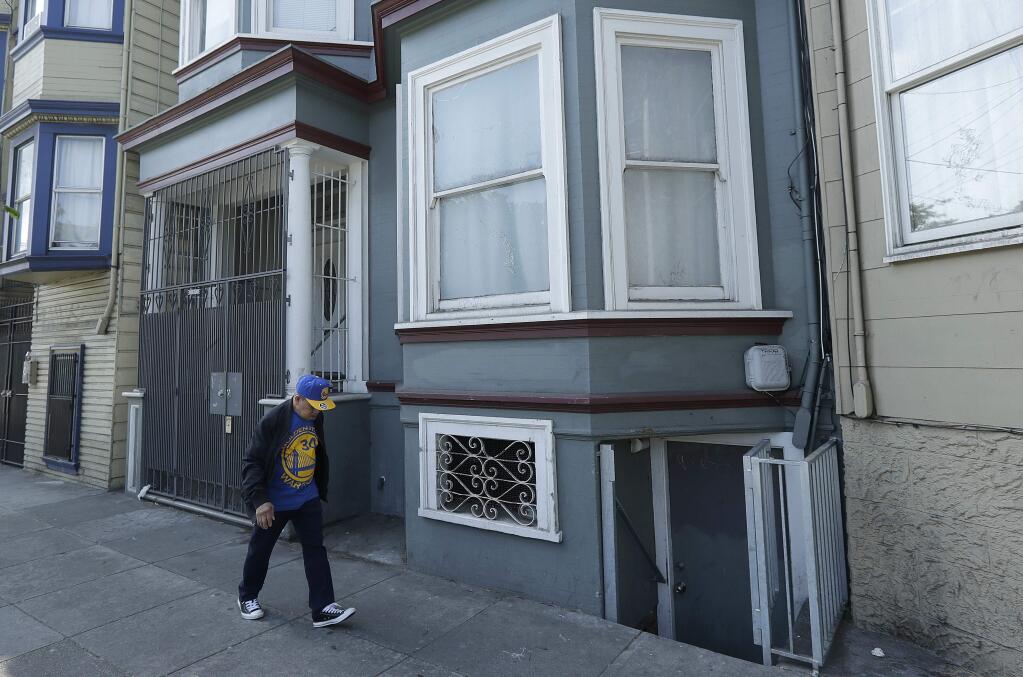 A man walks past a multi-unit property where a woman was charged with murder in the slaying of her roommate in San Francisco, Thursday, June 7, 2018. A dismembered body was discovered in oozing plastic bags inside a maggot-filled storage container at their home, prosecutors said Wednesday. (AP Photo/Jeff Chiu)