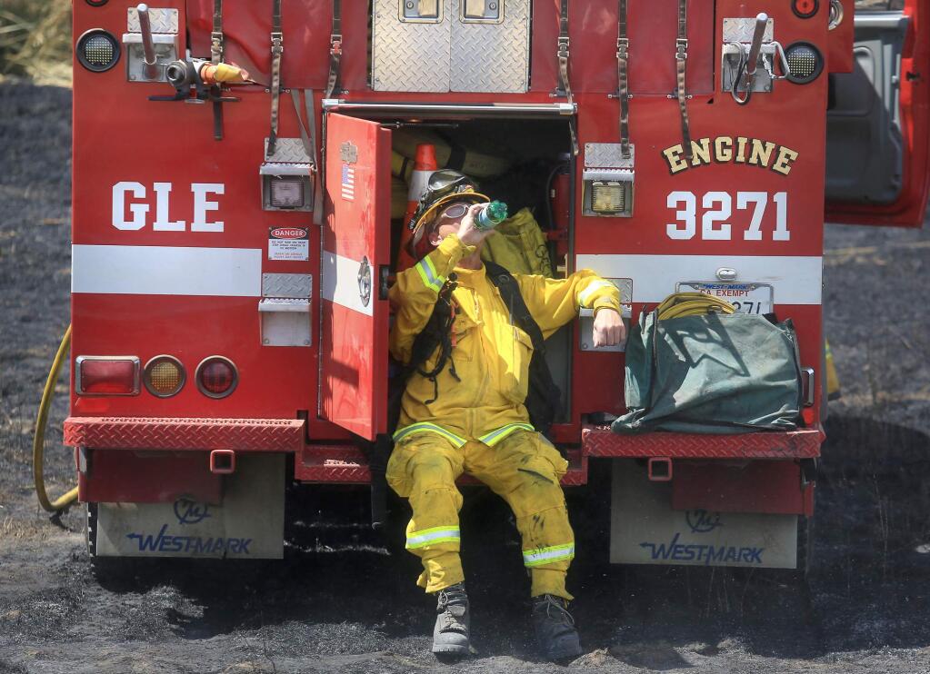 Glen Ellen firefighter George Psaledakis cools off after helping to contain a brush fire above the Petaluma valley floor on Sonoma Mountain, Tuesday June 30, 2015. (Kent Porter / Press Democrat) 2015