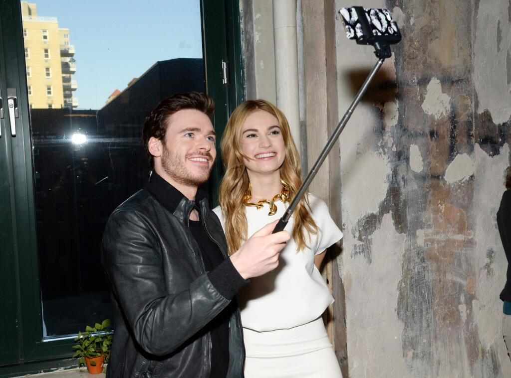 Actors Richard Madden and Lily James take a selfie while attending AOL's BUILD Speaker Series to discuss their new film 'Cinderella' at AOL Studios on Monday, March 9, 2015, in New York. Selfie sticks have been added to a list of banned items at several music festivals across the nation, including Coachella and Lollapalooza. (Photo by Evan Agostini/Invision/AP)