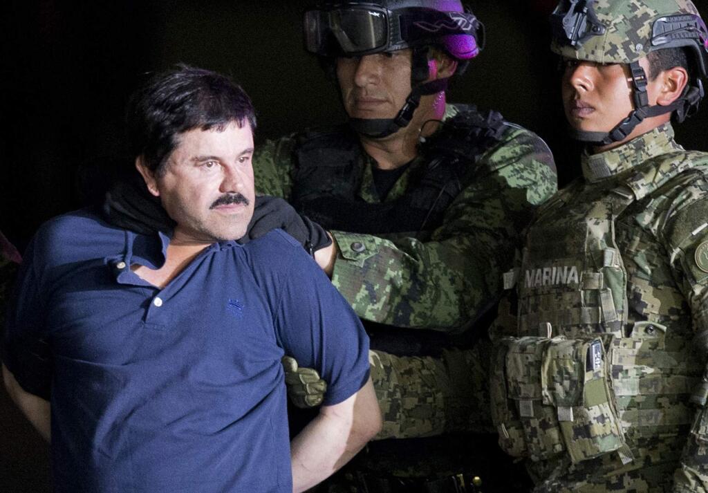 FILE - In this Jan. 8, 2016 file photo, a handcuffed Joaquin 'El Chapo' Guzman is made to face the press as he is escorted to a helicopter by Mexican soldiers and marines at a federal hangar in Mexico City. Mexico's most notorious cartel kingpin who twice made brazen prison escapes and spent years on the run as the country's most wanted man, was extradited to the United States on Thursday, Jan. 19, 2017, to face drug trafficking and other charges. (AP Photo/Eduardo Verdugo, File)