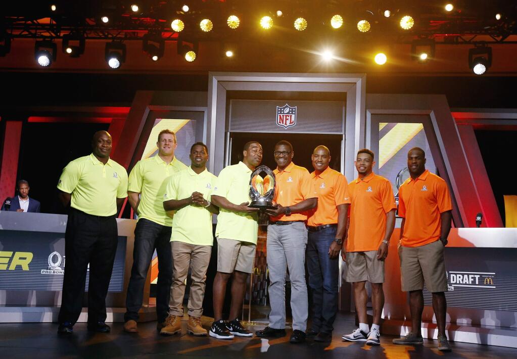 From left, John Randle, NFL Hall of Fame member and Team Carter Pro Bowl Alumni Co-Captain, Houston Texans Pro Bowl player J.J. Watt, Pittsburgh Steelers Pro Bowl player Antonio Brown, Cris Carter, NFL Hall of Fame member and Team Carter Pro Bowl Alumni Captain, Michael Irvin, NFL Hall of Fame member and Team Irvin Pro Bowl Alumni Captain, Darren Woodson, NFL Hall of Fame member and Team Irvin Pro Bowl Alumni Co-Captain, Cleveland Browns Pro Bowl player Joe Haden, and Dallas Cowboys Pro Bowl player DeMarco Murray, pose for photographers with the Pro Bowl Trophy during the Pro Bowl Kickoff news conference Tuesday, Jan. 20, 2015, in Phoenix. (AP Photo/Ross D. Franklin)