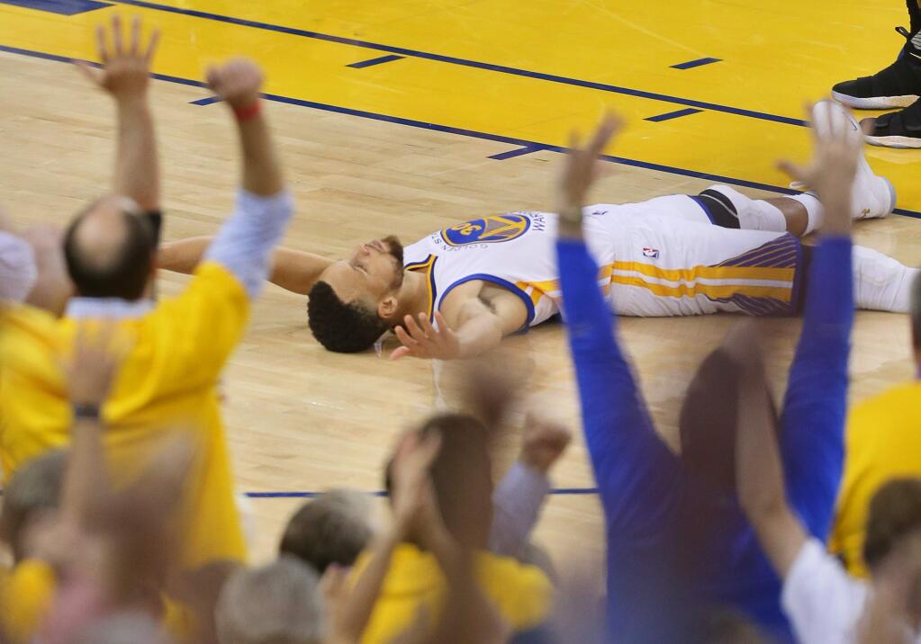 Golden State Warriors guard Stephen Curry lays on the court after sinking the shot and getting the foul call against the Cleveland Cavaliers, during Game 5 of the NBA Finals in Oakland on Monday, June 12, 2017. (Christopher Chung/ The Press Democrat)
