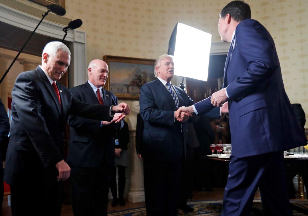 FILE - In this this Jan. 22, 2017, file photo, Vice President Mike Pence, left, and Secret Service Director Joseph Clancy stand as President Donald Trump shakes hands with then-FBI Director James Comey during a reception for inaugural law enforcement officers and first responders in the Blue Room of the White House in Washington. Comey is blasting Trump as ‚Äúunethical and untethered to truth,‚Äù and says Trump‚Äôs leadership of the country is ‚Äúego driven and about personal loyalty.‚Äù Comey‚Äôs comments come in a new book in which he casts Trump as a mafia boss-like figure who sought to blur the line between law enforcement and politics. (AP Photo/Alex Brandon, File)