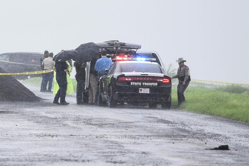 Law enforcement officers gather near the scene where the body of a woman was found near Interstate 35 north of Laredo, Texas on Saturday, Sept. 15, 2018. A U.S. Border Patrol agent suspected of killing four women was arrested early Saturday after a fifth woman who had been abducted managed to escape from him and notify authorities, law enforcement officials said, describing the agent as a 'serial killer.' (Danny Zaragoza/The Laredo Morning Times via AP)