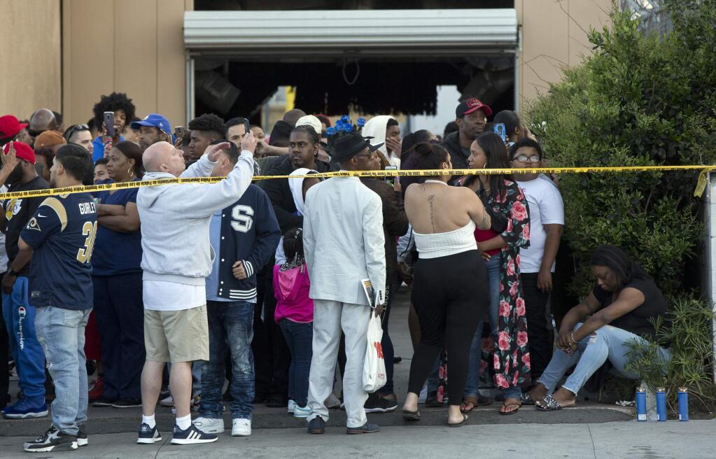 People gather near the Marathon Clothing store of rapper Nipsey Hussle in Los Angeles, Sunday, March 31, 2019. (AP Photo/Damian Dovarganes)