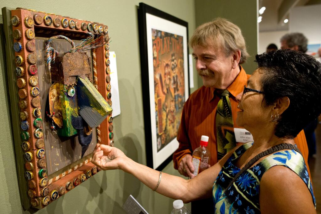 Vivian Rodriguez and John Viso examine a junk art piece called F R Heads created by artist 3D Edddy during Art for Life, an art auction benefitting Face to Face to help end HIV and AIDS in Sonoma County, on Sept. 6, 2014. (Alvin Jornada / For The Press Democrat)