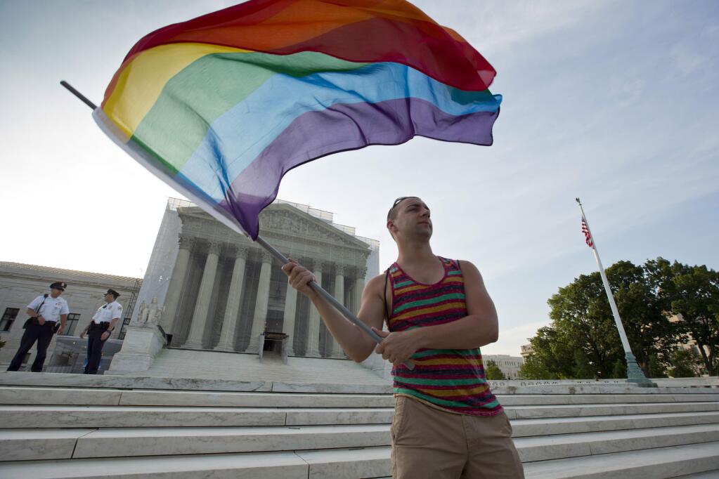 FILE- In this June 26, 2013, file photo, gay rights advocate Vin Testa waves a rainbow flag in front of the Supreme Court in Washington. Thousands of businesses, religious groups, advocacy organizations and politicians who are filing legal briefs at the Supreme Court in support of gay marriage. The cases from Kentucky, Michigan, Ohio and Tennessee will be argued April 28, and a decision is expected by early summer. (AP Photo/J. Scott Applewhite, File)