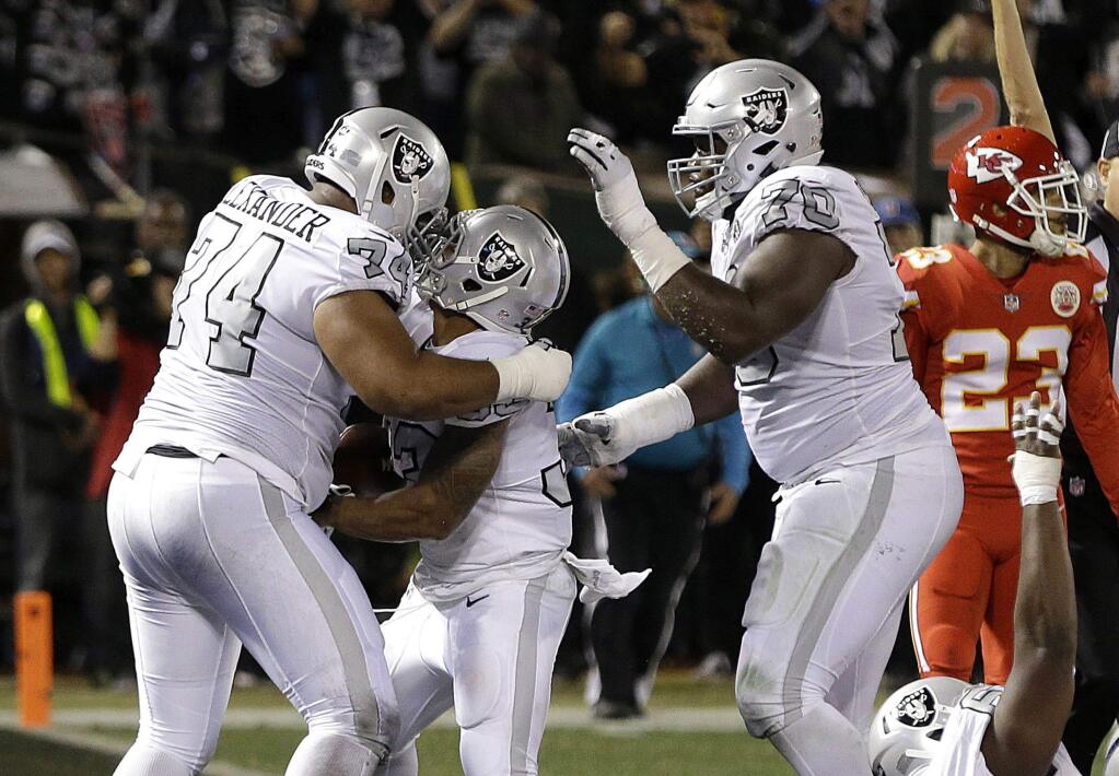 Oakland Raiders running back DeAndre Washington, center, is congratulated by offensive tackle Vadal Alexander (74) and offensive guard Kelechi Osemele after scoring a touchdown against the Kansas City Chiefs during the second half, Thursday, Oct. 19, 2017. (AP Photo/Ben Margot)
